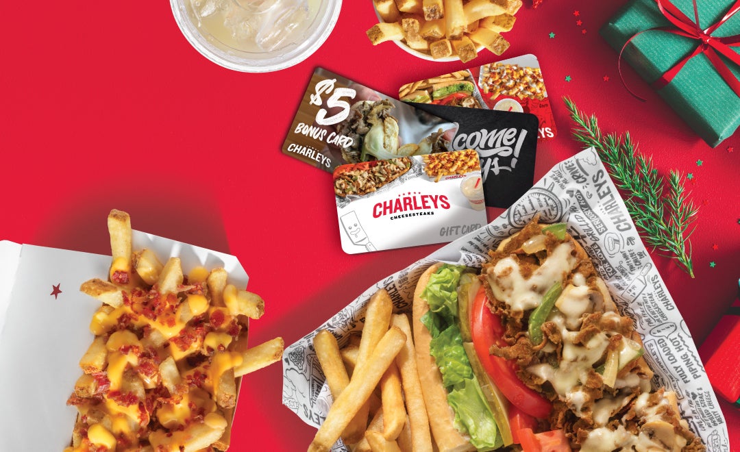 Charleys Cheesesteaks gift cards and bonus cards on a table with holiday decorations. Charleys gift card